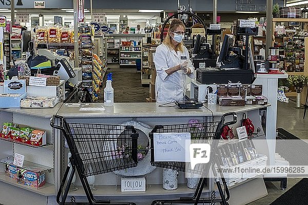 St. Paul Minnesota A cashier in a drugstore puts on her protective gloves while shopping carts keep people at a distance when paying for their purchases at the counter.