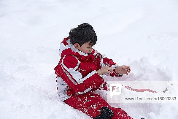 Boy playing in the snow  gloves and vest with snow.