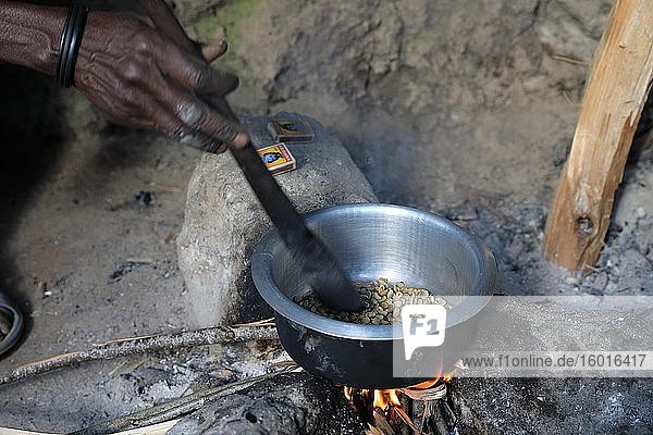 Woman preparing coffee over the fire  roasting coffee beans  Uganda  Africa