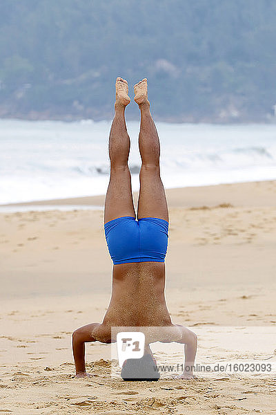 Mann macht Morgengymnastik am Strand
