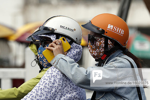 Zwei Frauen  die ein Motorrad fahren und ein Smartphone benutzen