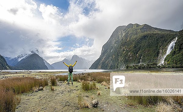 Young man jumps in the air  Mitre Peak  Bow Falls  Milford Sound  Fiordland National Park  Te Anau  Southland  South Island  New Zealand  Oceania