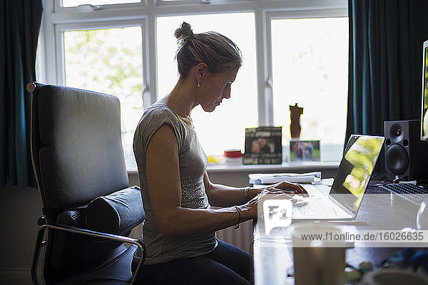 Frau  die von zu Hause aus am Laptop im Home-Office arbeitet