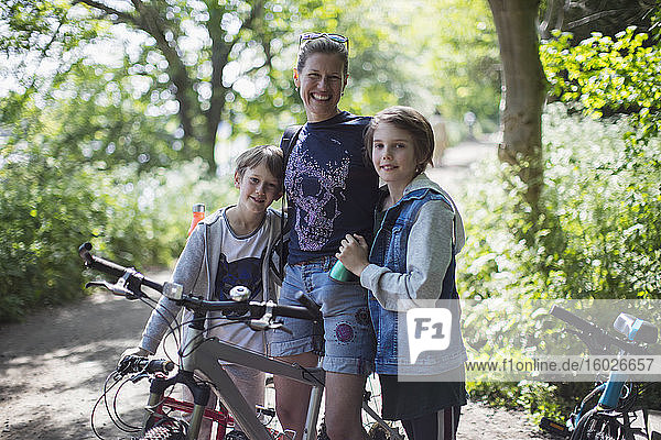 Porträt einer glücklichen Mutter und ihrer Söhne beim Radfahren in einem sonnigen Park