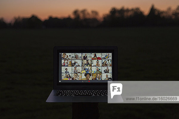 Video-Chat mit Freunden am Laptop-Bildschirm im Garten in der Abenddämmerung