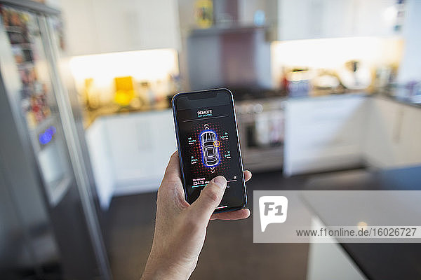 POV Mann sichert Autoalarm vom Bildschirm eines Smartphones in der Küche