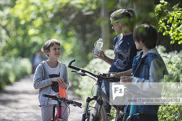 Mother and sons drinking water on bike ride