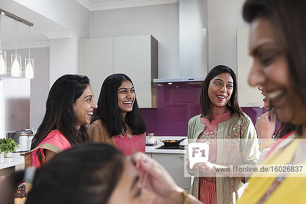 Glückliche indische Frauen in Saris sprechen in der Küche