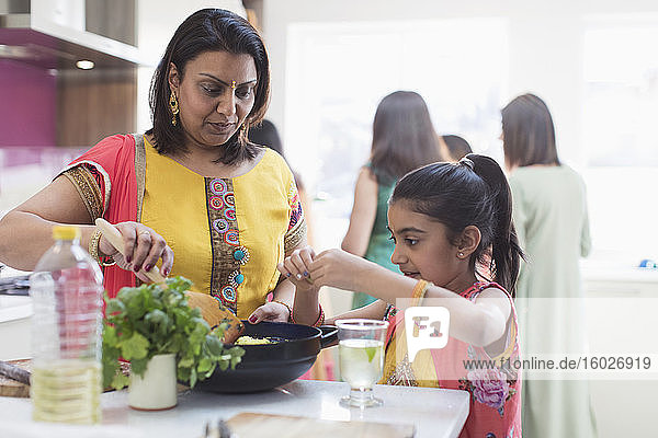 Indische Mutter und Tochter in Saris kochen Essen in der Küche