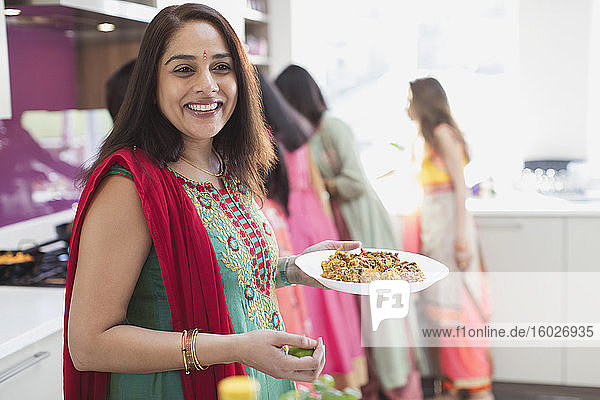 Porträt einer glücklichen indischen Frau in Sari beim Essen in der Küche
