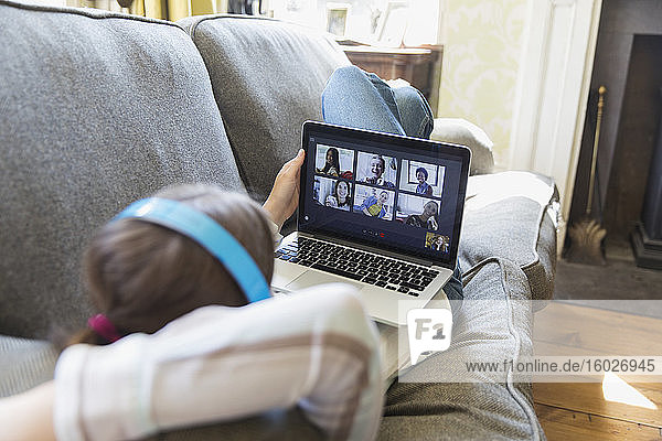 Video-Chat mit Freunden am Laptop-Bildschirm auf dem Wohnzimmer-Sofa