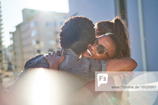 Glückliches junges Paar umarmt sich auf sonnigem Stadtbalkon