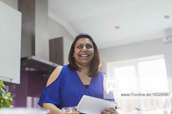 Portrait einer glücklichen Frau mit digitalem Tablett in der Küche