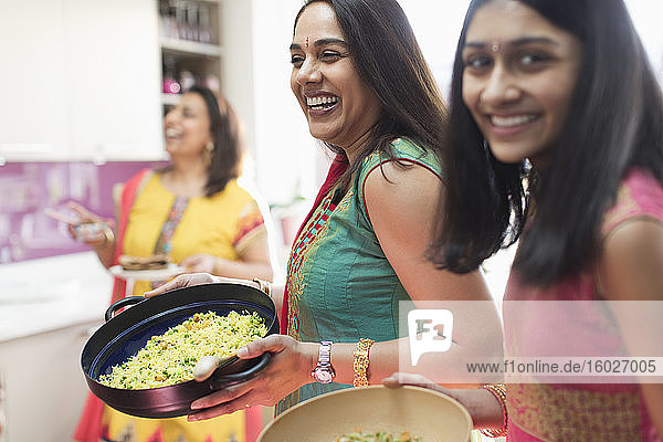 Glückliche indische Frauen in Saris kochen Essen in der Küche