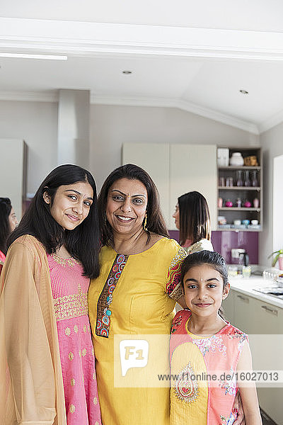 Portrait happy Indian mother and daughters in saris in kitchen