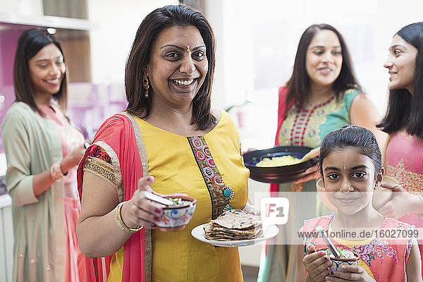 Portrait happy mother and daughter in Indian saris with food