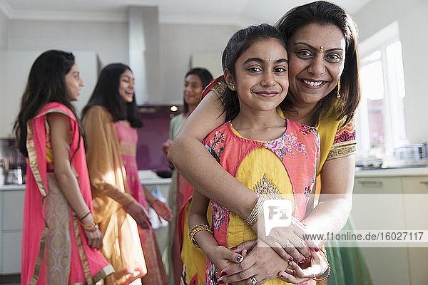 Portrait happy Indian mother and daughter in saris hugging