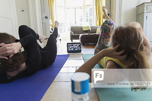 Mutter und Tochter nehmen zu Hause am Online-Yoga-Kurs teil