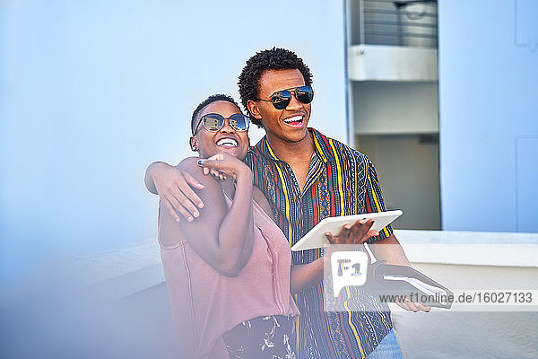 Glückliches junges Paar mit digitalem Tablett auf dem Balkon