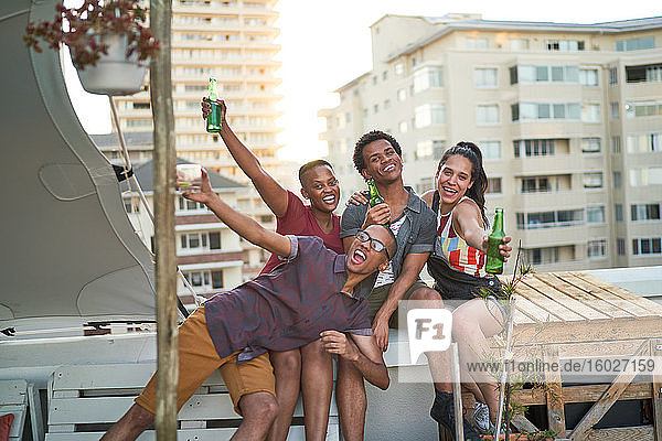 Porträt sorgloser junger Freunde beim Biertrinken auf dem städtischen Dachbalkon