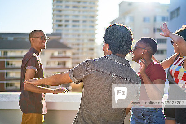 Unbeschwerte junge Freunde tanzen auf dem sonnigen Dach der Stadt