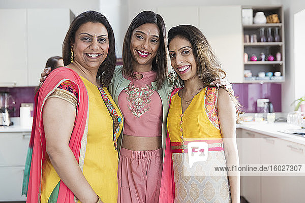 Porträt glücklicher indischer Schwestern in Saris in der Küche