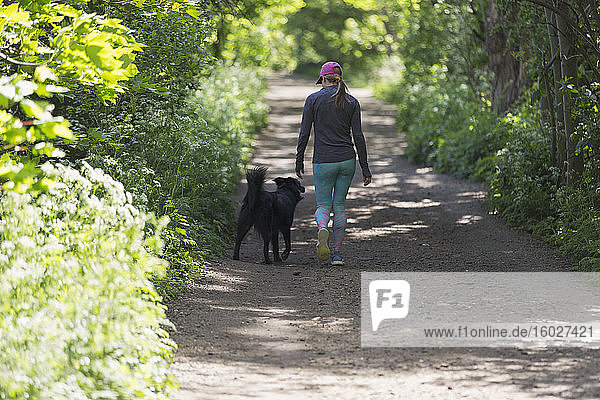 Woman walking on trail with dog