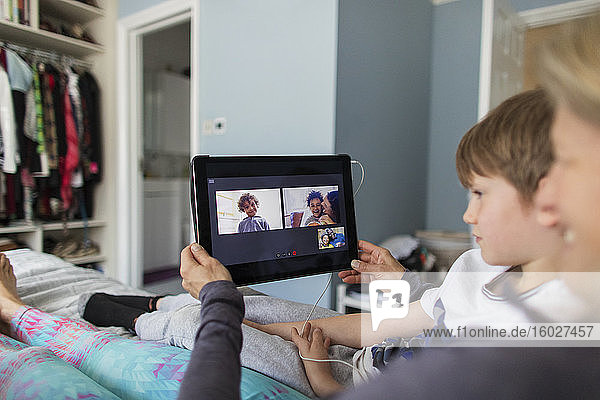 Family video chatting with digital tablet on bed