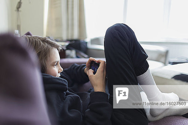 Junge spielt Videospiel mit Smartphone auf dem Sofa