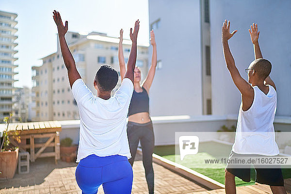 Freunde praktizieren Yoga auf einem sonnigen städtischen Dach