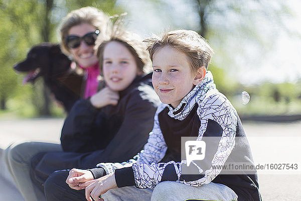 Porträt Mutter und Söhne mit Hund im sonnigen Park