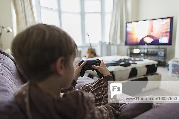 Boy playing video game on living room sofa