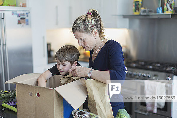 Mutter und Sohn beim Ausladen der Produkte aus dem Karton in der Küche