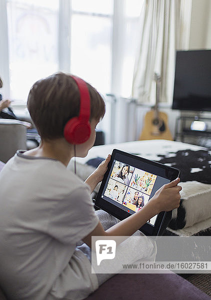 Boy with headphones and digital tablet homeschooling on sofa