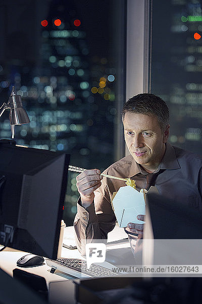 Geschäftsleute essen abends am Schreibtisch im Büro