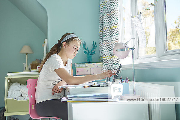 Fokussierter Heimunterricht für Mädchen am Schreibtisch im Schlafzimmer