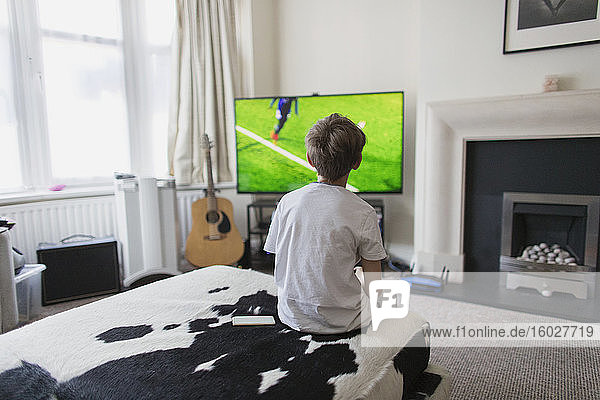 Junge schaut im Wohnzimmer ein Fußballspiel im Fernsehen