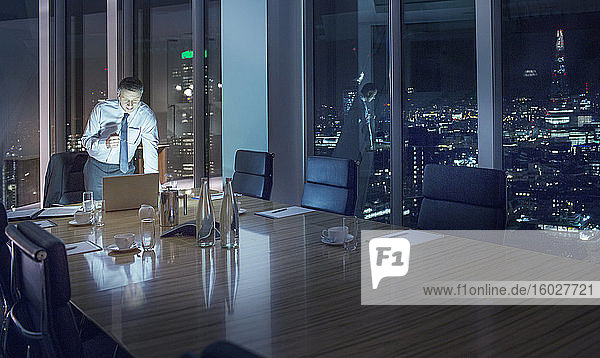 Businessman working late at laptop in conference room