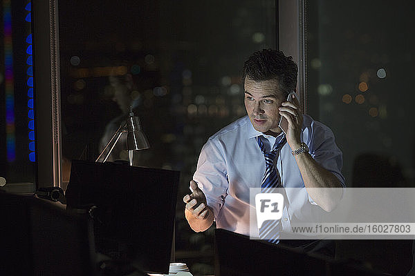 Geschäftsmann telefoniert nachts im Büro per Handy