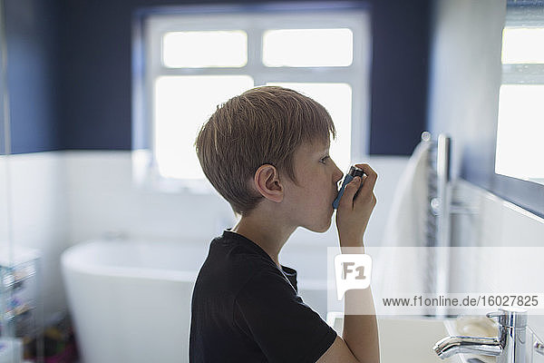 Junge mit Asthma benutzt Inhalator im Badezimmer