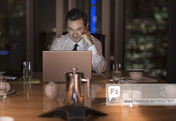Geschäftsmann arbeitet nachts spät am Laptop im Konferenzraum