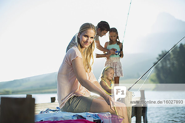 Lächelnde Frau mit Familie beim Angeln am Dock über dem See