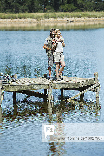 Smiling couple hugging on dock over lake