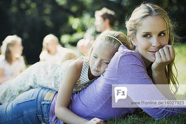 Gelassene Mutter und Tochter im Gras liegend