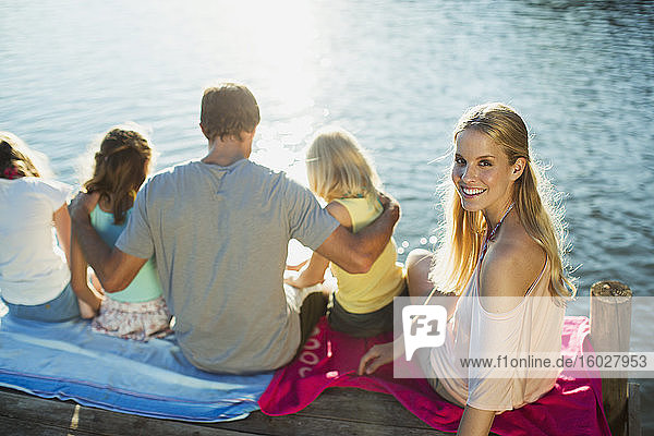 Lächelnde Frau mit Familie am Dock über dem See