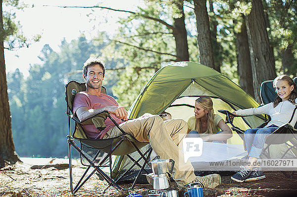 Lächelnde Familie entspannt sich auf einem Campingplatz im Wald