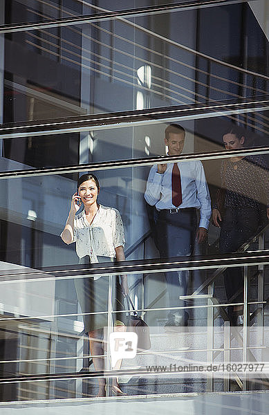 Lächelnde Geschäftsfrau benutzt Mobiltelefon am Fenster