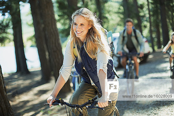Lächelnde Frau beim Fahrradfahren im Wald