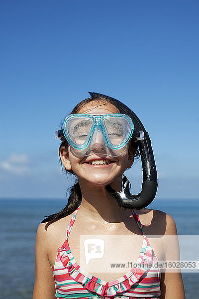 Happy girl wearing snorkel and goggles on beach