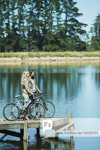 Paar mit Fahrrädern auf dem Dock mit Blick auf den See